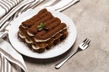 Classic tiramisu dessert on ceramic plate on concrete background