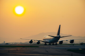 Fototapeta na wymiar Aircraft taxiing to airport runway under sunset