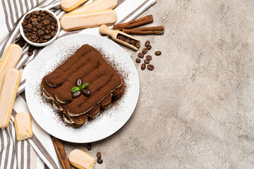 Classic tiramisu dessert and savoiardi cookies on ceramic plate on concrete background