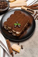 Classic tiramisu dessert and savoiardi cookies on ceramic plate on concrete background