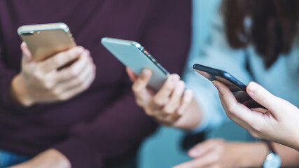 Group of young people using and looking at mobile phone while sitting together