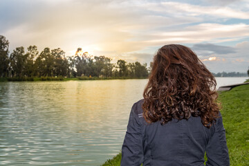 Real woman watching the sunset on a lake.