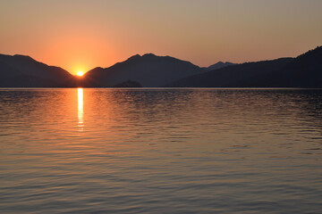 The sun rises from behind the mountains on the seaside