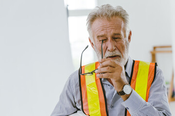 An elderly man worker removed glasses because of eyes irritation or stress from hard working.