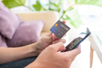 Selective focus shot at credit card mock up. Asian men hand holding credit card while type information into mobile smartphone device to made payment for online shopping. Technology, finance concept.