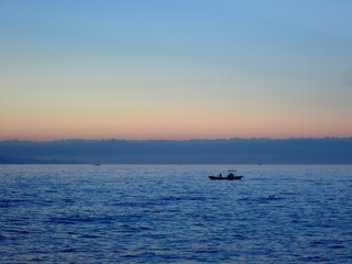Naklejka na ściany i meble 夜明けのグラデーションになった空のもと穏やかな海に浮かぶ釣り船