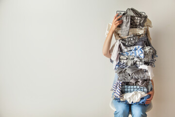 Surprised woman holding metal laundry basket with messy clothes on white background. - obrazy, fototapety, plakaty