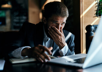 A business man in a suit is sitting in a cafe or with a laptop the work is an official