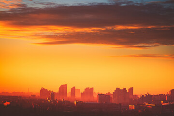 Fototapeta na wymiar Sunset aerial Europe town silhouette: Kyiv cityscape at sun set golden tones cloudy sky. Ukrainian capital urban architecture with high skyscrapers, houses, buildings. Majestic european scenery view