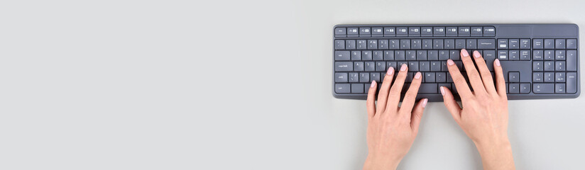 Hands with keyboard on grey background. Flat lay, overhead view image.
