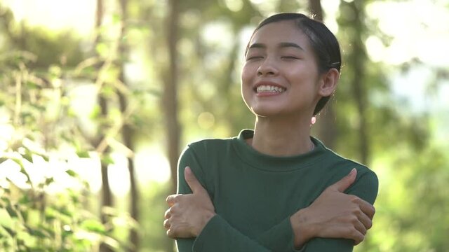 Asian woman hugging herself, looks happy for love your self concept. Slow motion.
