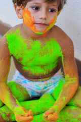 Portrait of cute child who is bathed in colored powders during Holi