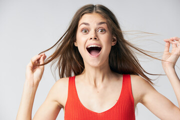 happy woman in a red t-shirt touches the hair on her head with her hands 