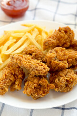 Homemade Crispy Chicken wings and French Fries with sour-sweet sauce on cloth, side view.