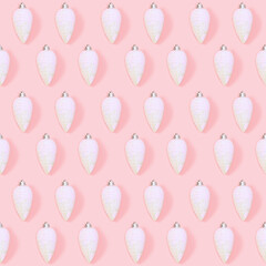 Seamless regular creative Christmas pattern with white New Year toys in shape of pine cones on millennial pink paper.