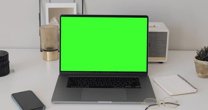 Zoom in shot. MacBook Pro Laptop with Green Mock-up Screen Display Standing on the Desk of the Bright and Cozy Apartment Living Room. 