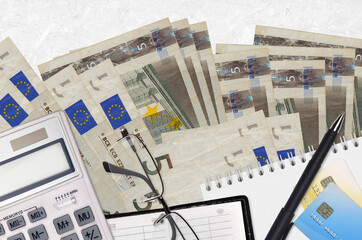 5 euro bills and calculator with glasses and pen. Tax payment concept or investment solutions. Financial planning or accountant paperwork