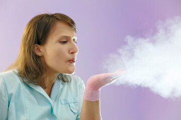 Woman in green uniform and pink gloves blowing white powder.