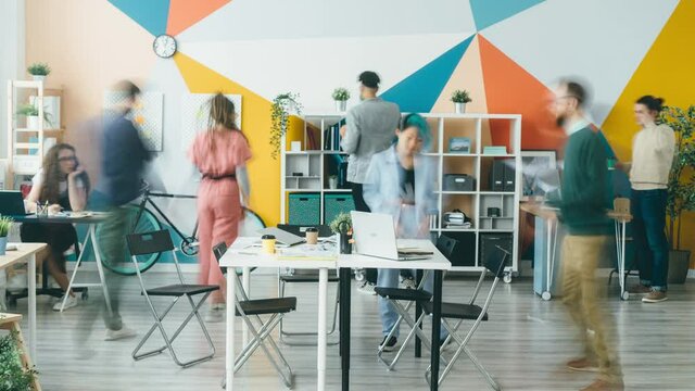 Time lapse of diverse group of young people working in modern office talking cooperating moving around. Creative workplace and employees concept.