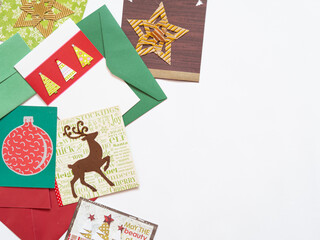 Top view of christmas cards with holiday motives as trees, reindeer and star. Flat lay on white background with copy space. 