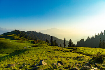 Fototapeta premium lush green mountain line and meadows landscape from the top hill with clear blue sky and forest 