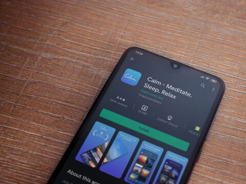 Lod, Israel - July 8, 2020: Calm App Play Store Page On The Display Of A Black Mobile Smartphone On Wooden Background. Top View Flat Lay With Copy Space.