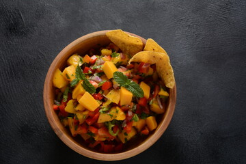 Salsa with mango, herbs, onions and peppers, corn chips close up in a bowl. Mexican Food.