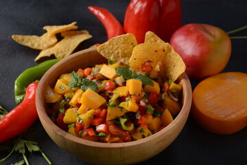 Salsa with mango, herbs, onions and peppers, corn chips close up in a bowl. Mexican Food.