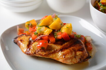 Grilled chicken breast with spicy salsa salad, mango, herbs, onions and peppers, corn chips. Mexican Food.