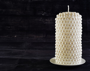 A close up of a large white candle on a black background to signify peace, solitude and remembrance.