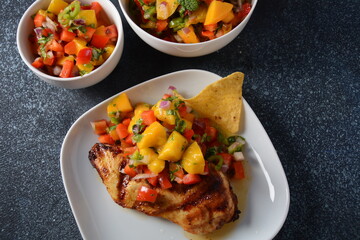 Grilled chicken breast with spicy salsa salad, mango, herbs, onions and peppers, corn chips. Mexican Food.
