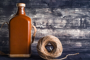 Vintage bottle of whiskey and a ball of thread for the interior on a dark wood background