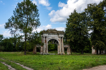 Fototapeta na wymiar ruins of an old manor house among green trees against a blue sky