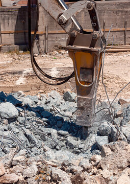 Concrete rubble debris on construction site, Crushed concrete slabs and steel bars,Demolition excavator with hydraulic jack hammer is destroying a Reinforced Concrete with recycle steel bar.