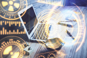 Computer on desktop in office with technology theme hologram. Double exposure. Tech concept.