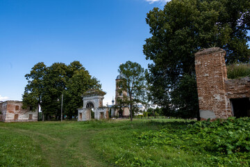 ruins of an old manor house among green trees against a blue sky