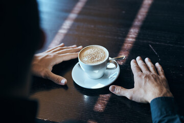 Cup of coffee on the table with white rice and a teaspoon of cafe mens hands.