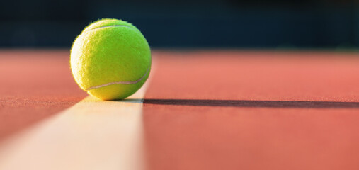 Bright greenish yellow tennis ball on the line.