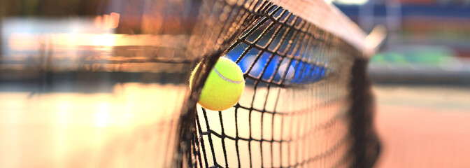 Bright greenish yellow tennis ball hitting the net. - obrazy, fototapety, plakaty