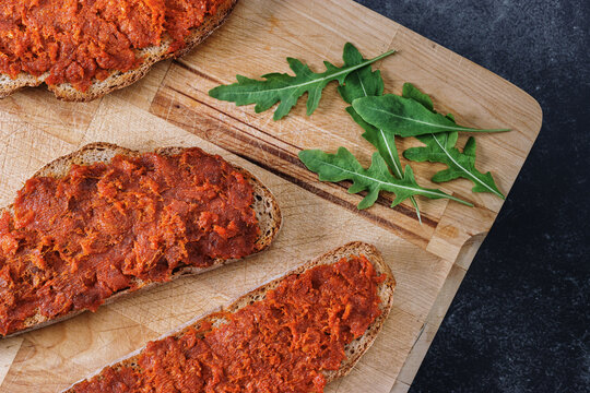Typical mallorcan food made of bread slices with meat spread &ldquo;sobrasada&rdquo; on a wooden cutting board. Traditional gastronomy of Majorca.