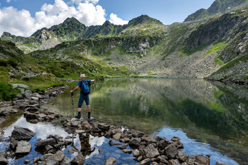 Senior hiker on the shore of the alpine lake, Porcile lakes, Orobie, Italian Alps