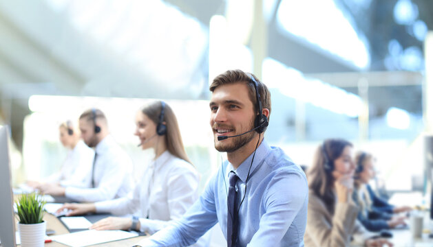 Portrait of call center worker accompanied by his team. Smiling customer support operator at work.