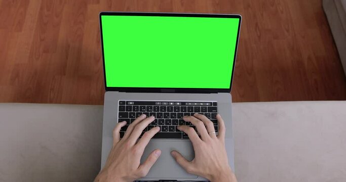 Close up shot, view from above. Hands of man typing code or message on green screen MacBook Pro. Online video conference, work or education concept. POV