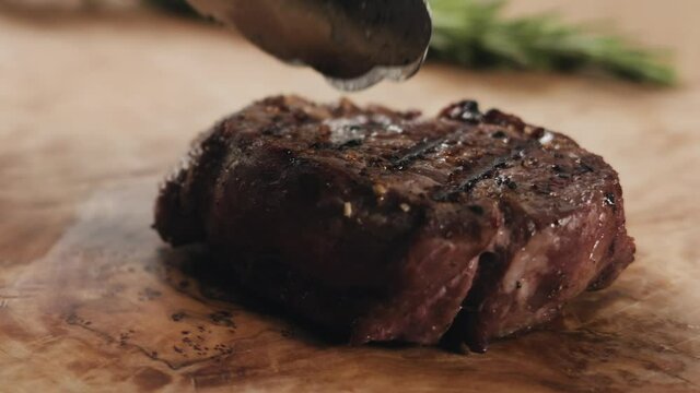 Slow motion slide slicing medium rare fillet mignon steak on wood board