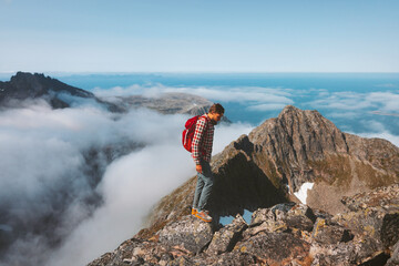 Man adventurer hiking in mountains with backpack travel outdoor trekking alone summer vacations activity healthy lifestyle trail in Norway above clouds