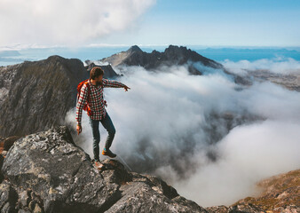 Man traveling hiking in mountains outdoor activity adventure vacations healthy lifestyle hiker guide on summit above clouds hand showing direction location