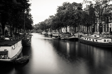 Fototapeta premium Amsterdam, Holland, the Netherlands - July 6 2020: capture of the typical Amsterdam scenery in black and white with canal, canalo house, clouds and the iconic buildings of the city