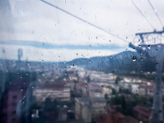Rain on the window in cable car and blurred city and powerlines
