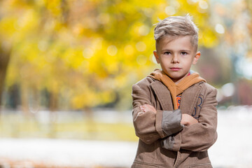 Cute little boy in autumn outfit over yellow background