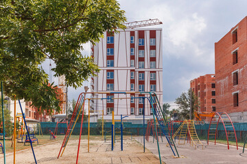 Fototapeta na wymiar Construction of a multi-storey buildings. Tower crane near the house. Sports ground on the background of a high-rise buildings